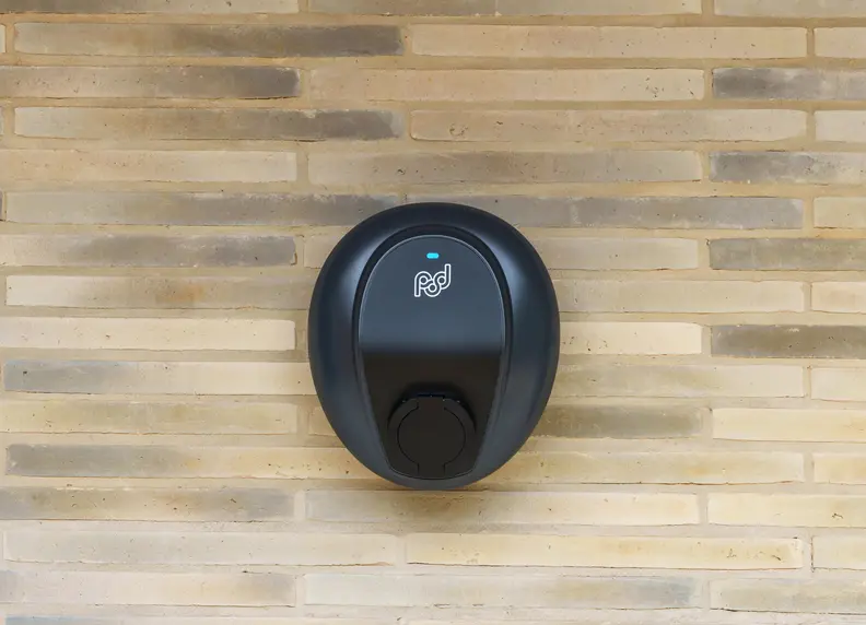 Socketed home charger on a light brick wall, without a cable attached